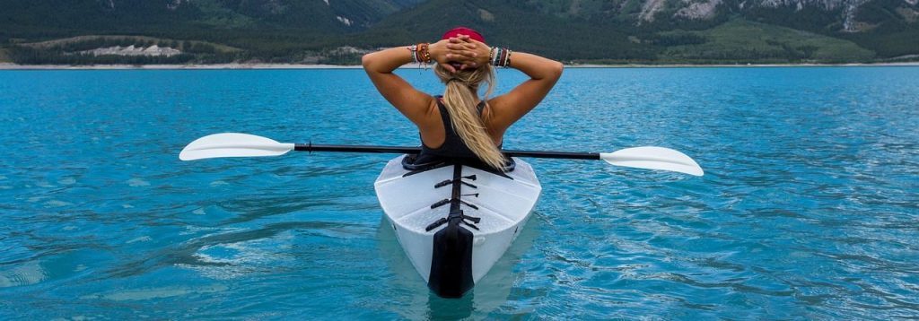 Family-friendly kayaking scene on a scenic mountain lake, featuring a relaxed paddler enjoying nature.